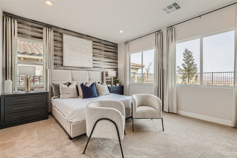 A bedroom with a bed and chairs.