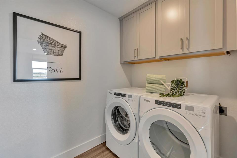 A white laundry room with a white washing machine and a white wall.