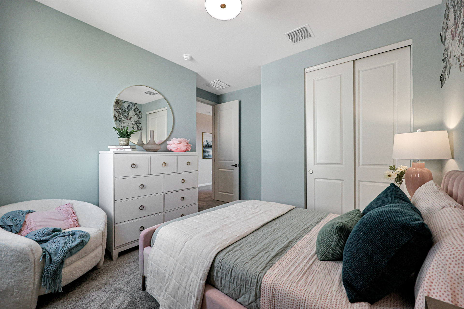 A bedroom with a bed and a mirror.