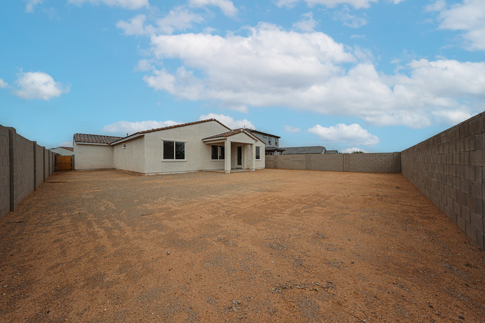 A dirt road with a house on the side.