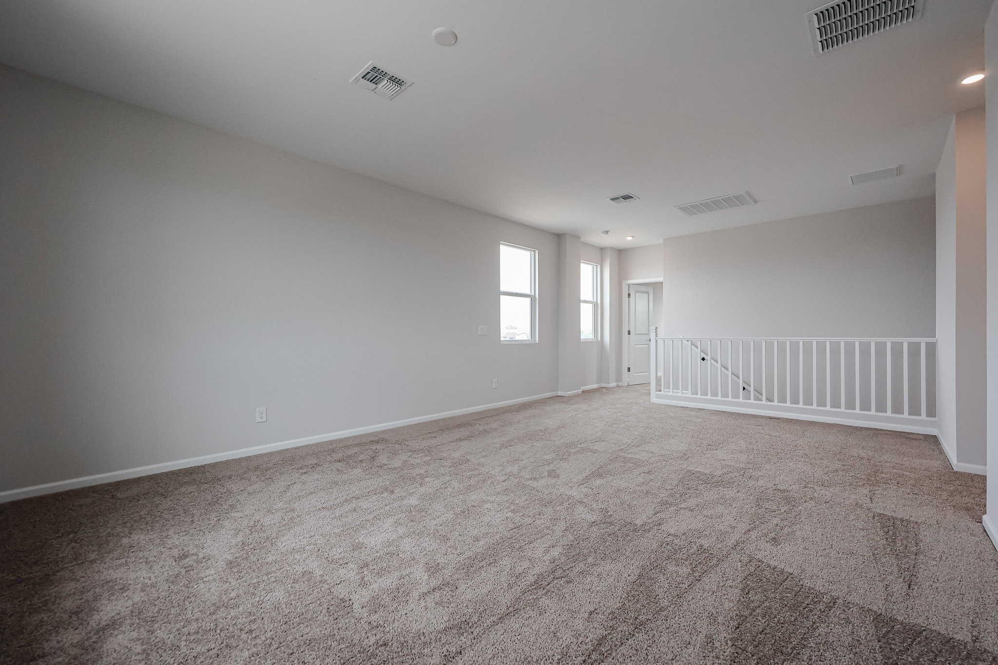 A room with a carpet and a white railing.