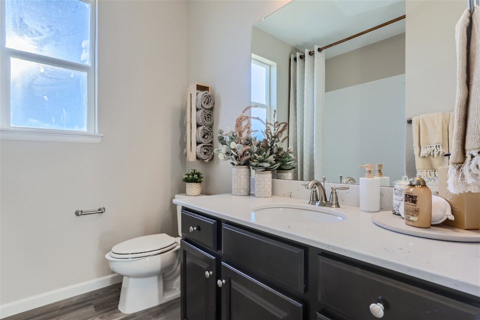 A bathroom with a sink toilet and mirror.