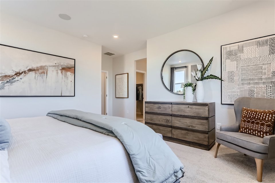 A bedroom with a bed and a chair.