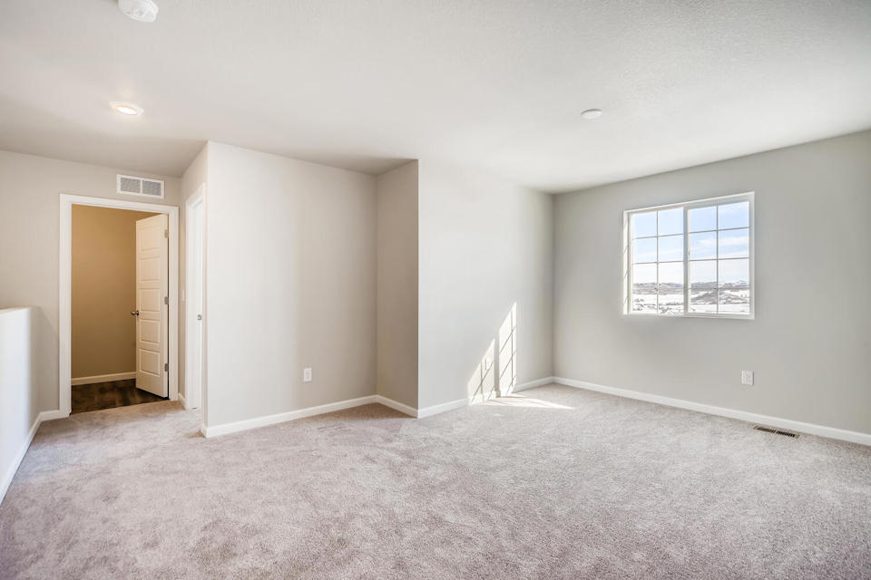 A room with a carpet and a staircase.