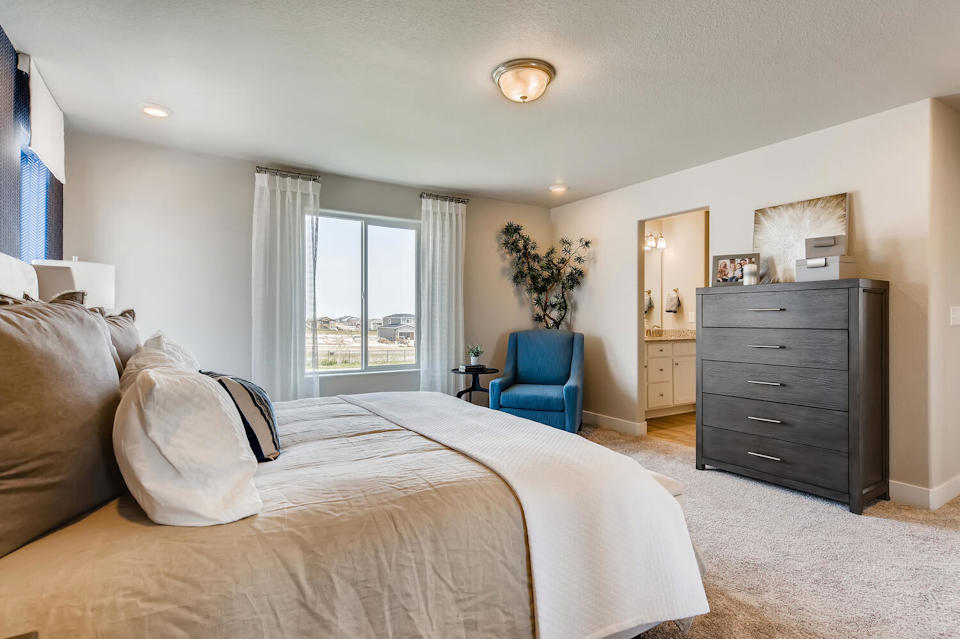 A bedroom with a bed and a chair.