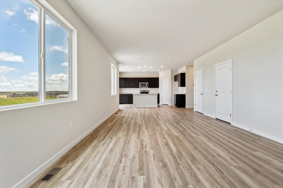 A room with a wood floor and a window with a view of the outside.