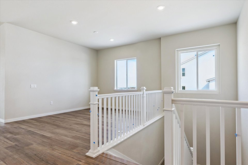 A room with a white railing and a wood floor with a white railing.