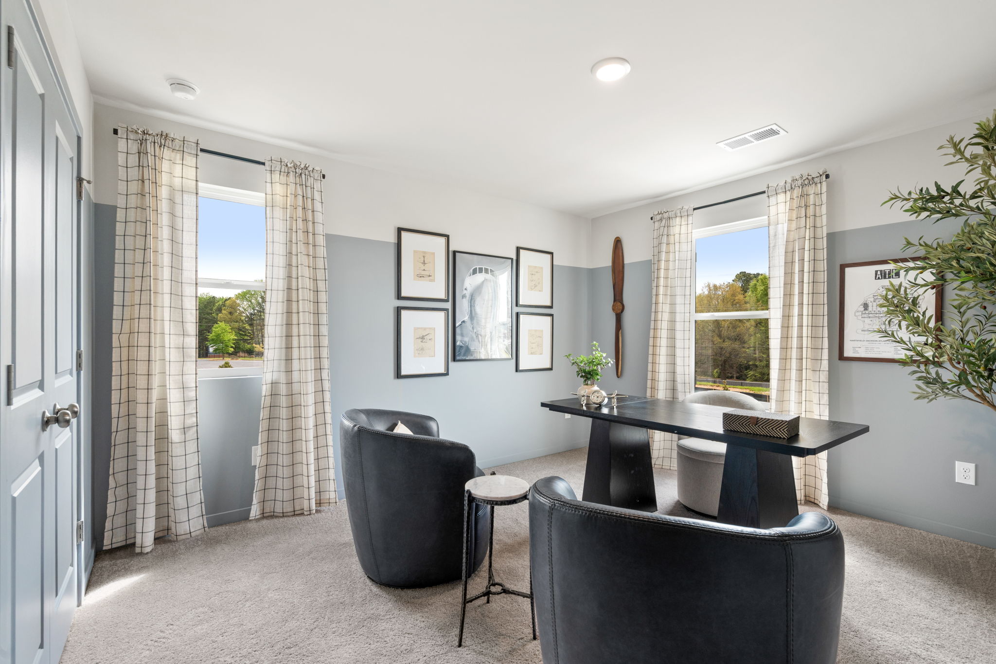 A room with a table chairs and a window with curtains.