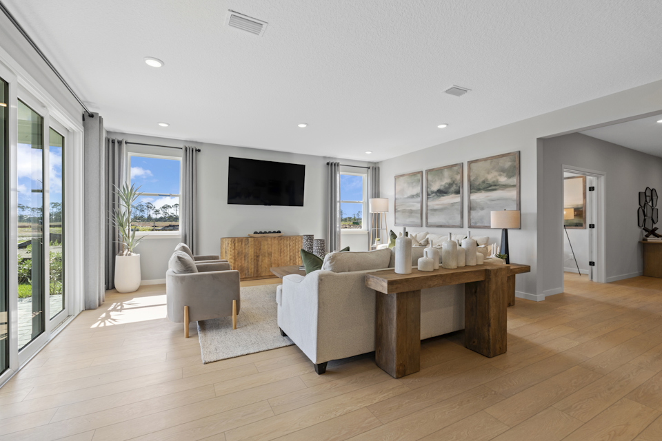 Kenai Model Home Living Room with Cream Couches and Large Sliding Patio Doors at Reserve East in Flagler Beach