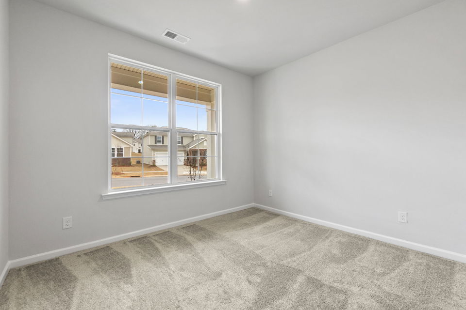 A room with a window and a white wall with a view of a city.