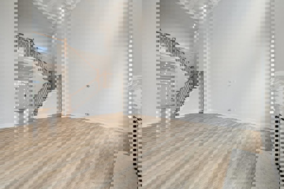 A large empty room with a wood floor and a staircase.