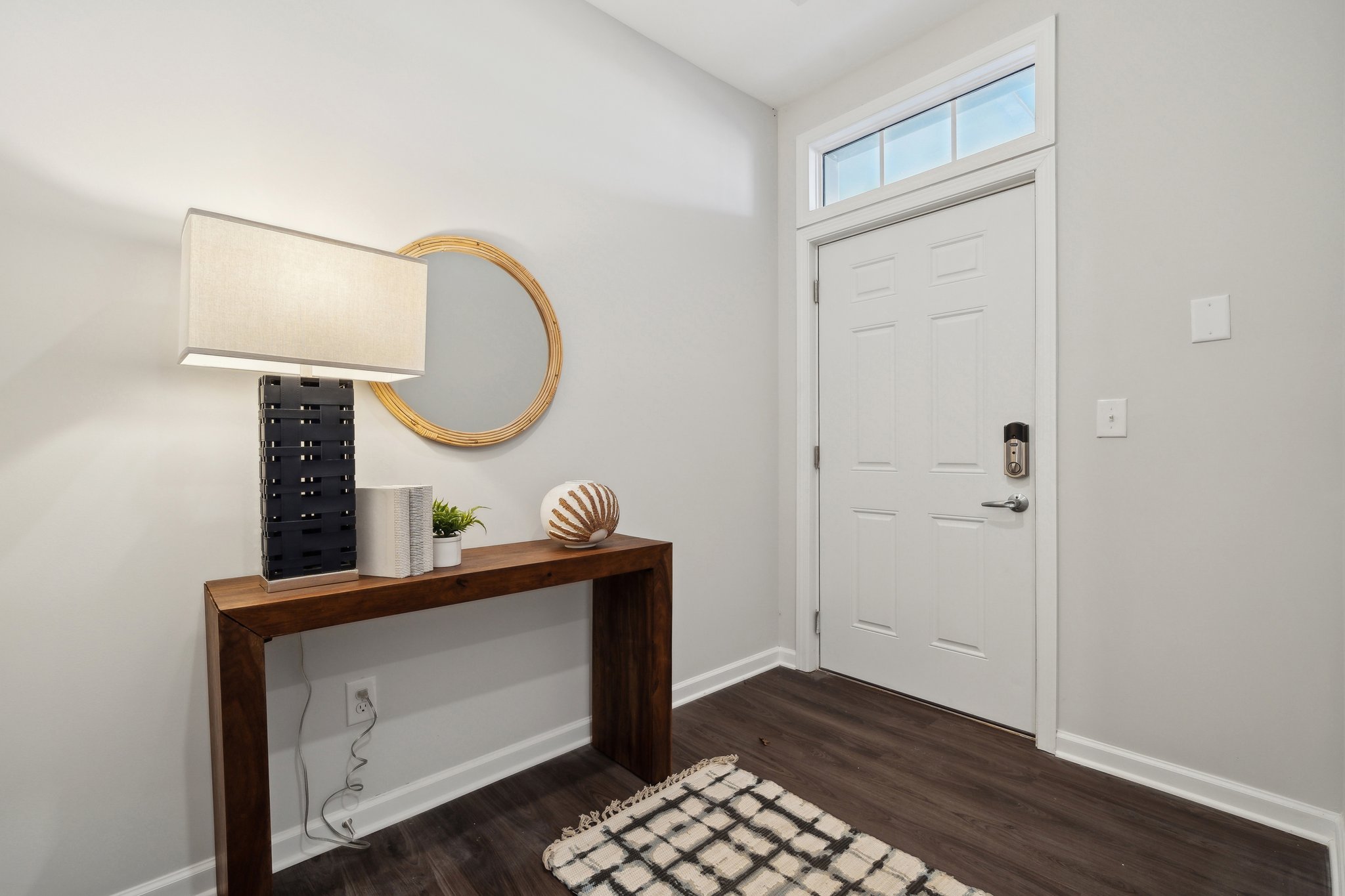 A room with a mirror and a table with a lamp on it.