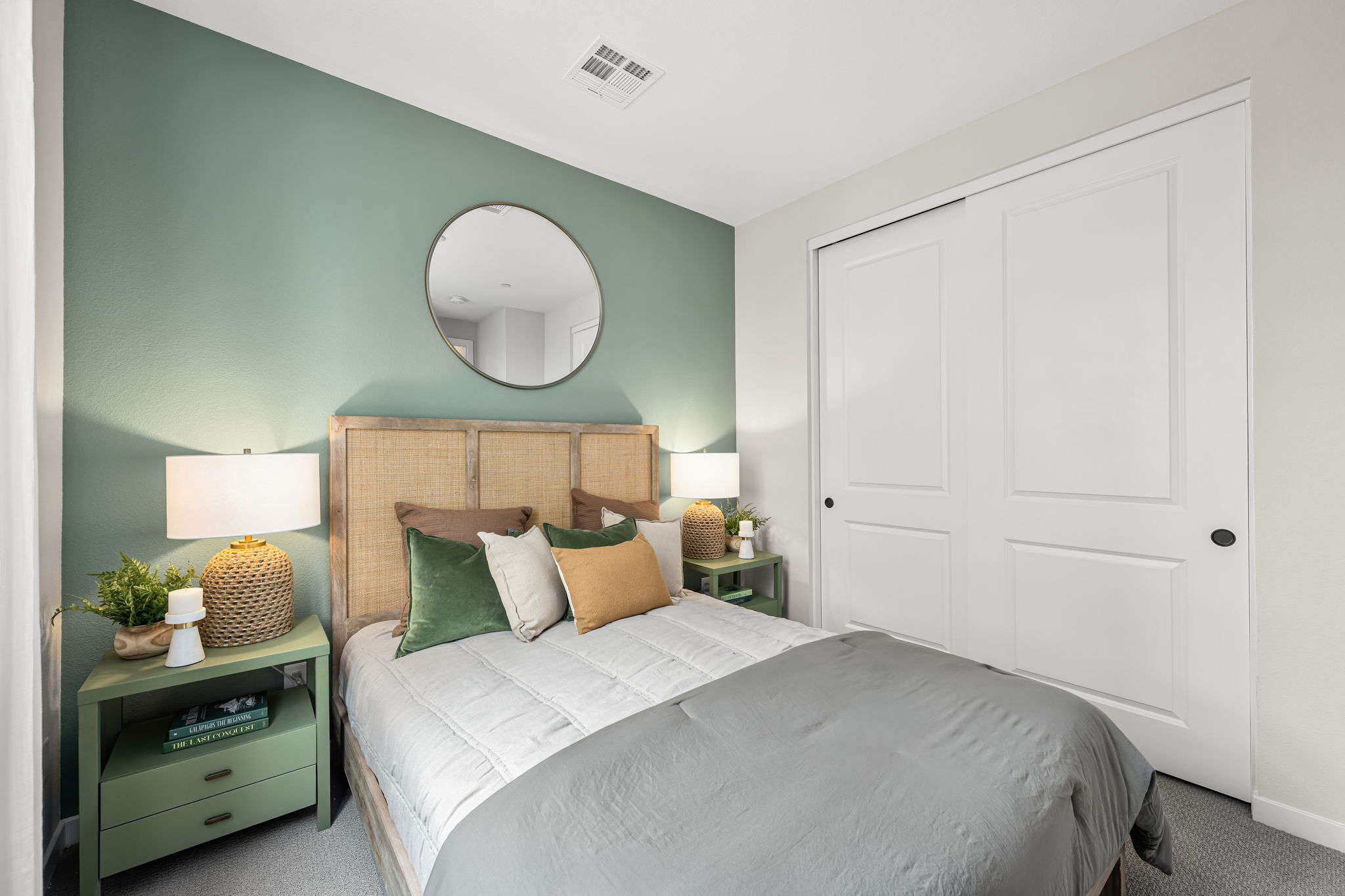 A bedroom with a bed and a mirror.