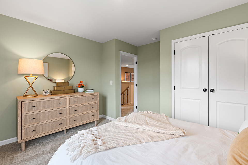A bedroom with a bed and dresser.