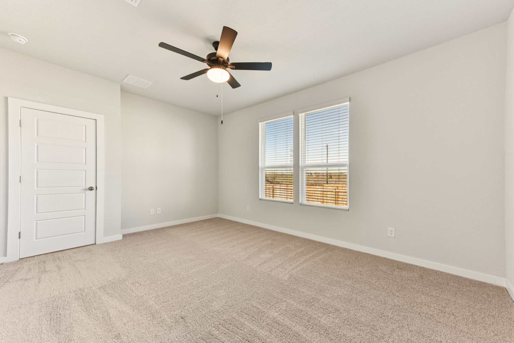 A room with a ceiling fan and a door.