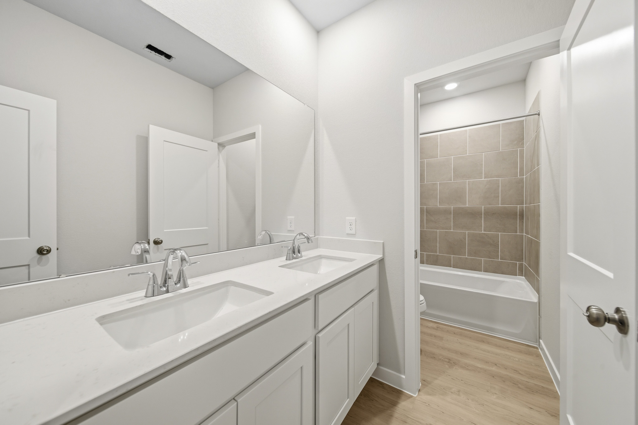 A bathroom with a tub sink and a mirror.