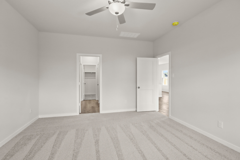 A room with a ceiling fan and a door.