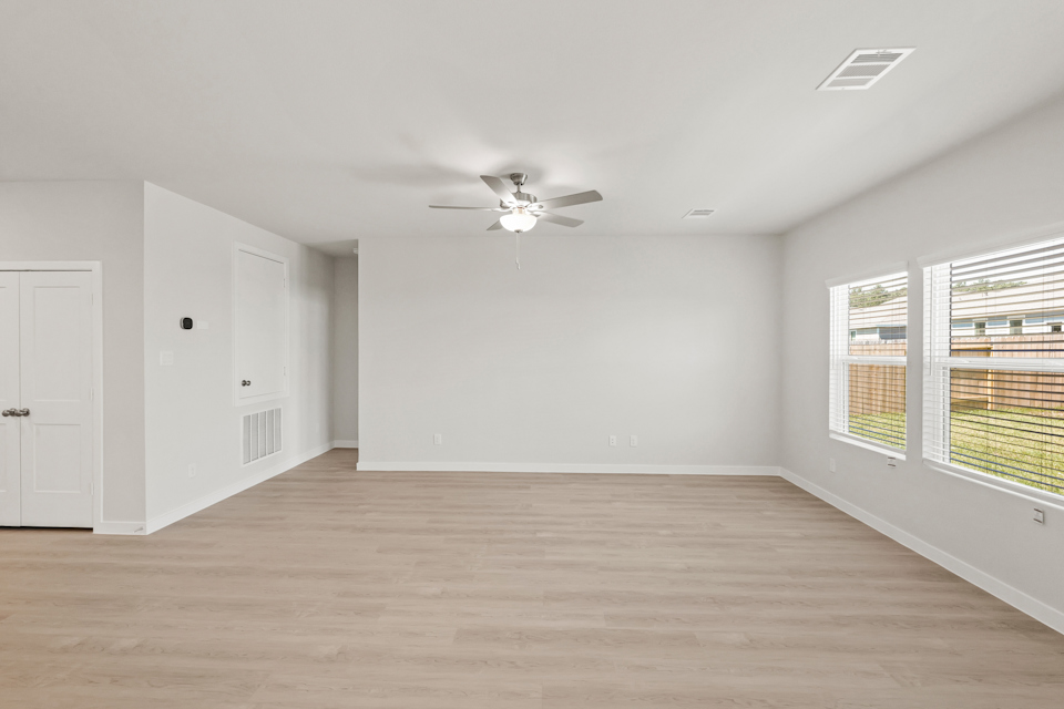 A room with a ceiling fan and a wood floor.