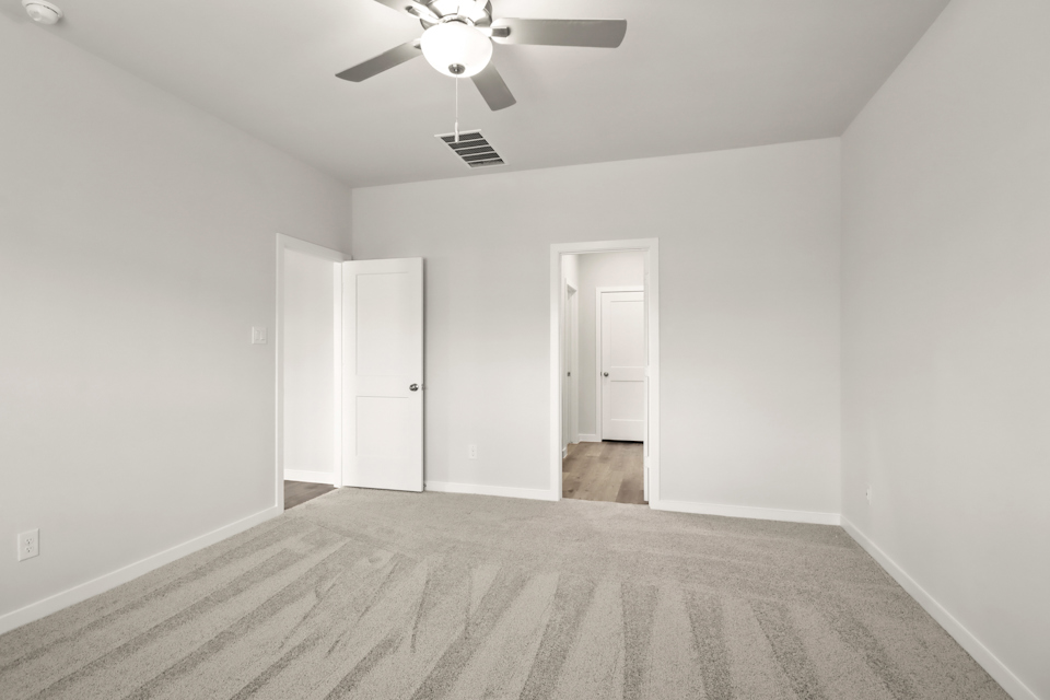 A room with a ceiling fan and a door.