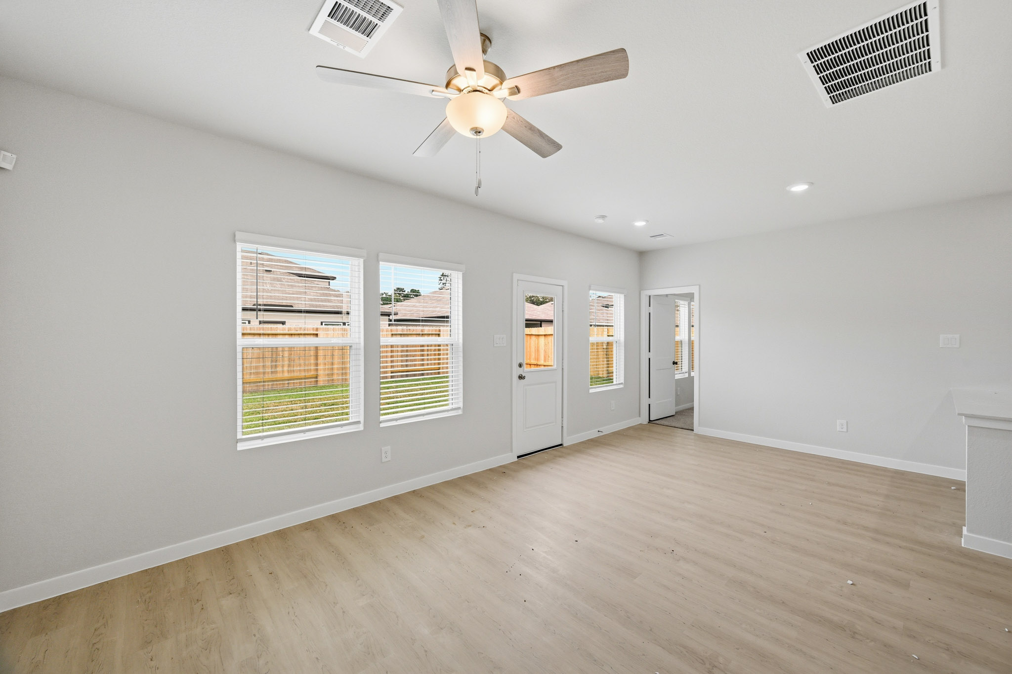 A room with a ceiling fan and a wood floor.