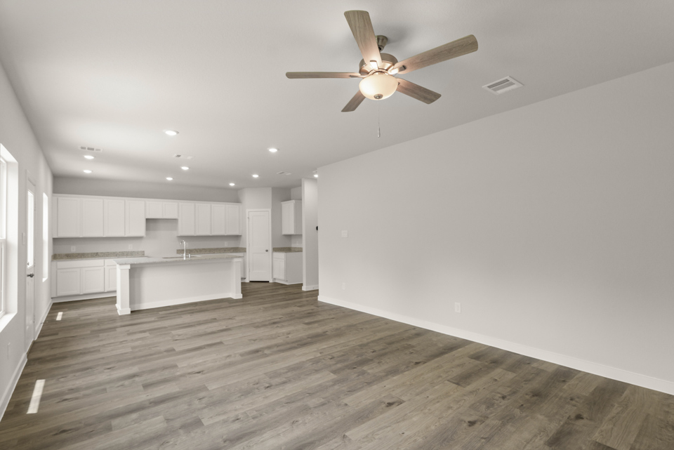 A room with a ceiling fan and white cabinets.