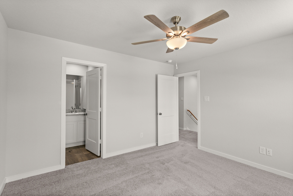 A room with a ceiling fan and a door.