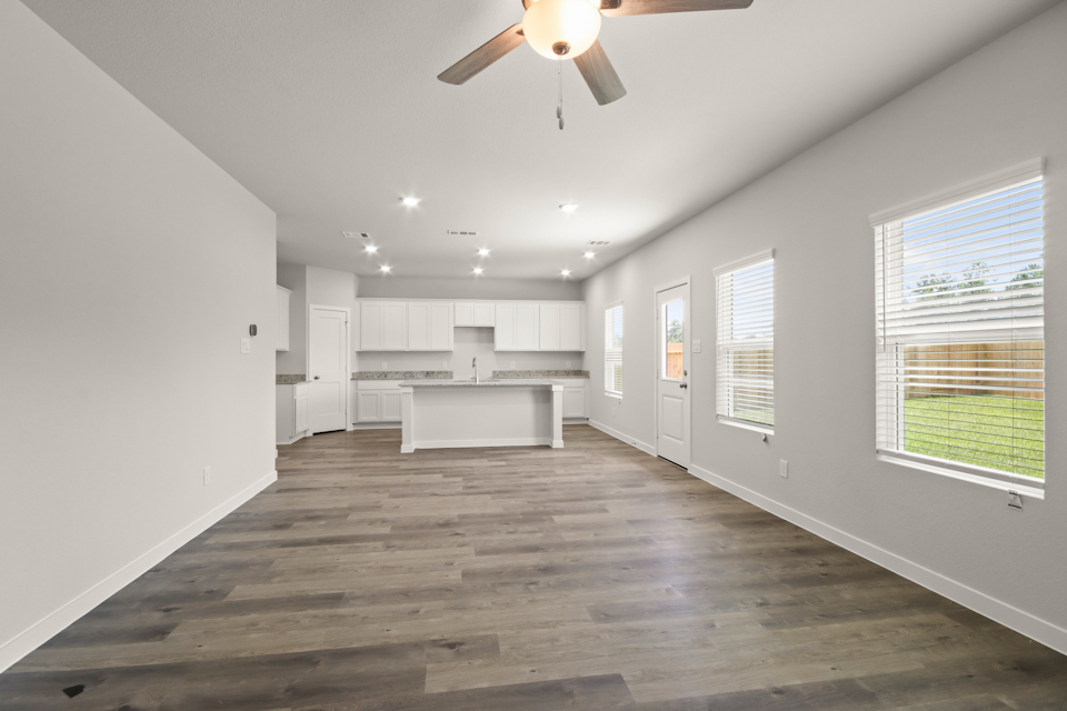 A large empty room with a ceiling fan and a wood floor.