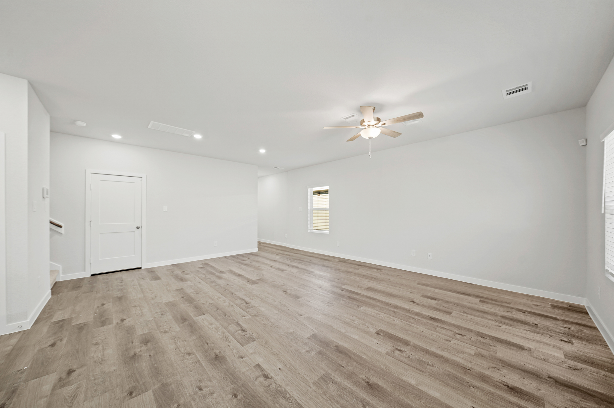 A room with a wood floor and a ceiling fan.