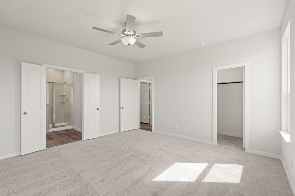 A room with a ceiling fan and white doors.