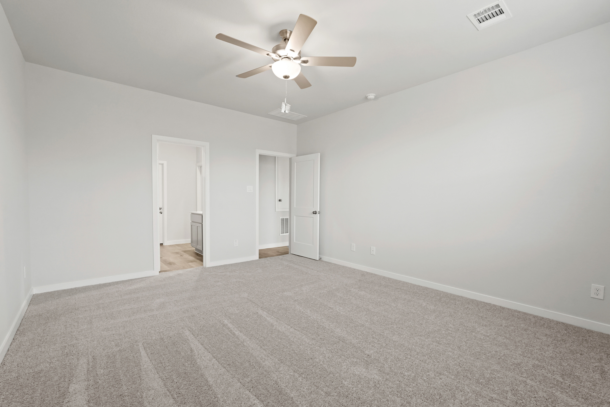 A room with a ceiling fan and a carpet.