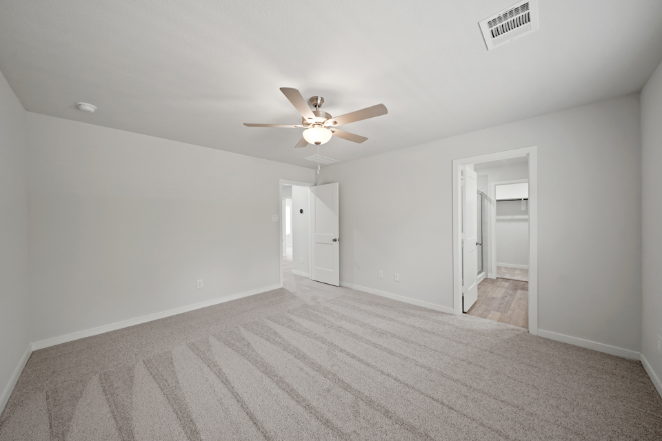 A room with a ceiling fan and a carpet.