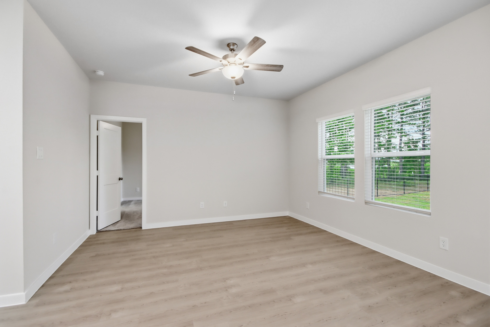 A room with a wood floor and a ceiling fan.