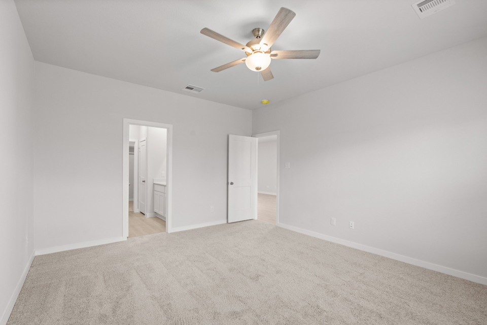 A room with a ceiling fan and a carpet.