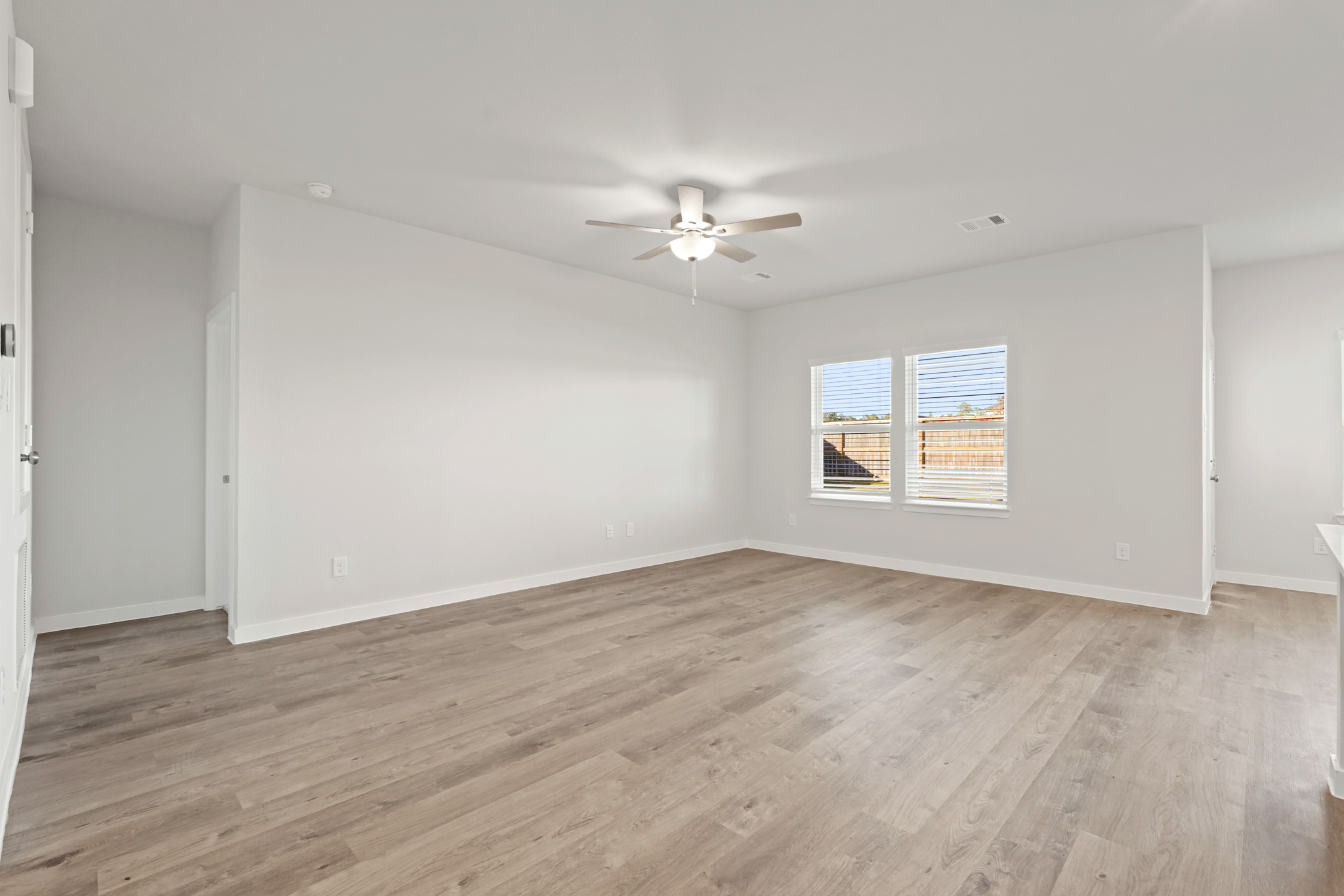 A room with a wood floor and a ceiling fan.