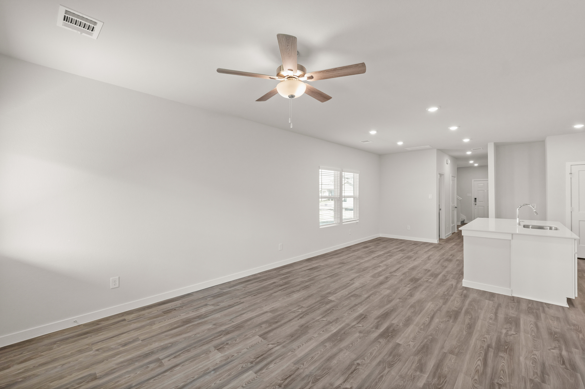 A room with a ceiling fan and a wood floor.