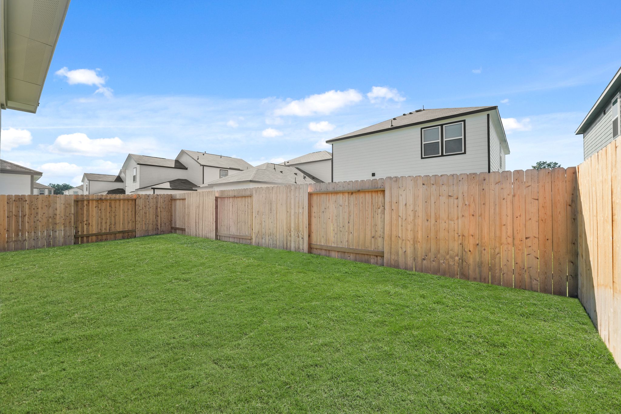 A fenced in yard with a house in the background.