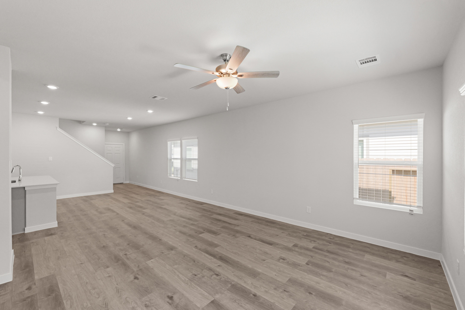 A room with a ceiling fan and a wood floor.