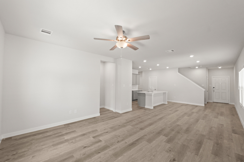 A room with a ceiling fan and a wood floor.