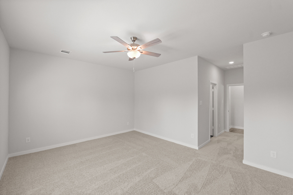 A room with a ceiling fan and a carpet.
