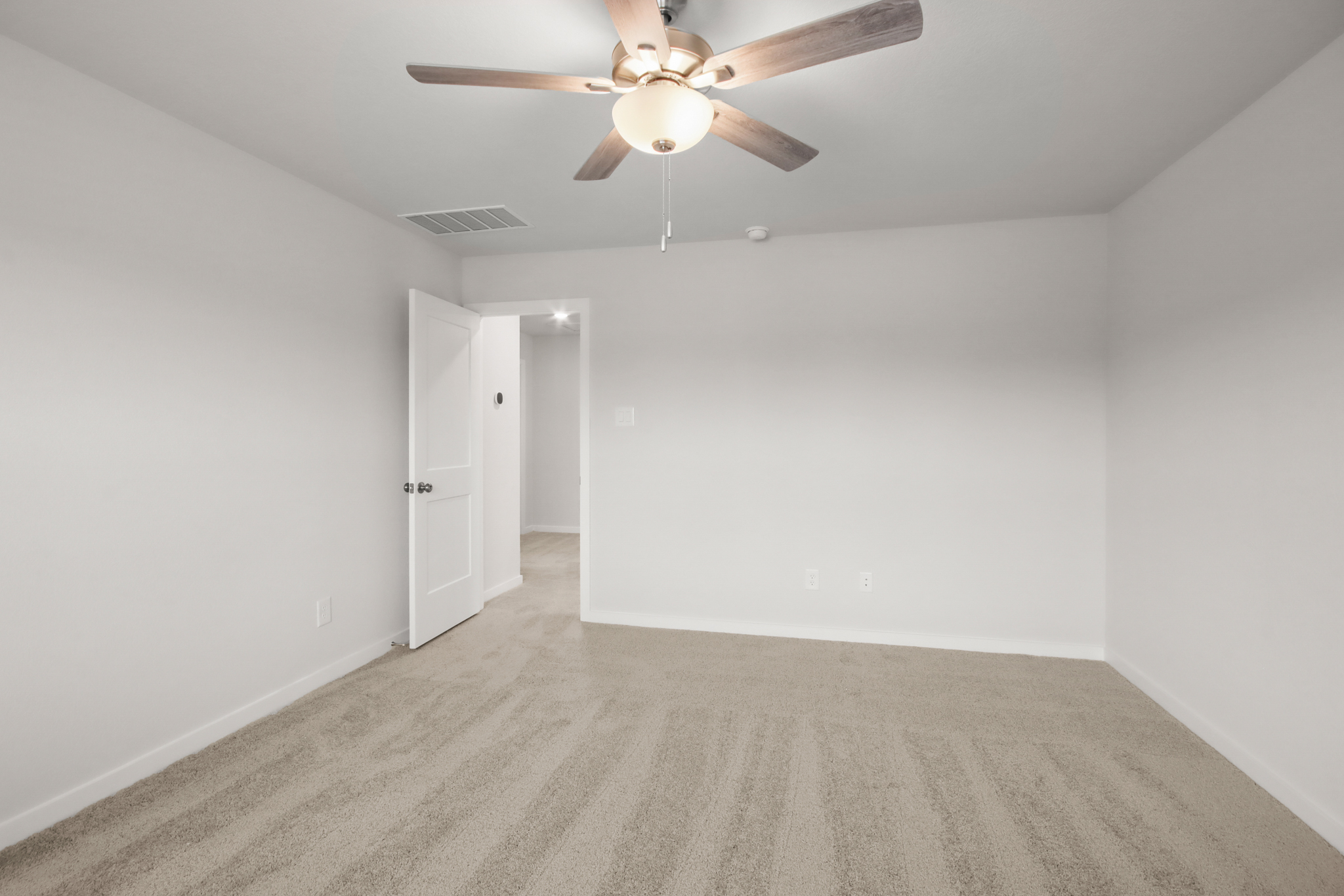A room with a ceiling fan and a carpet.