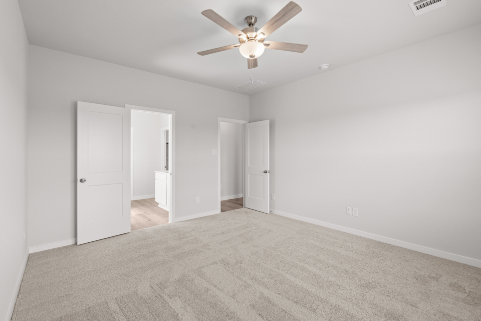 A room with a ceiling fan and white doors.