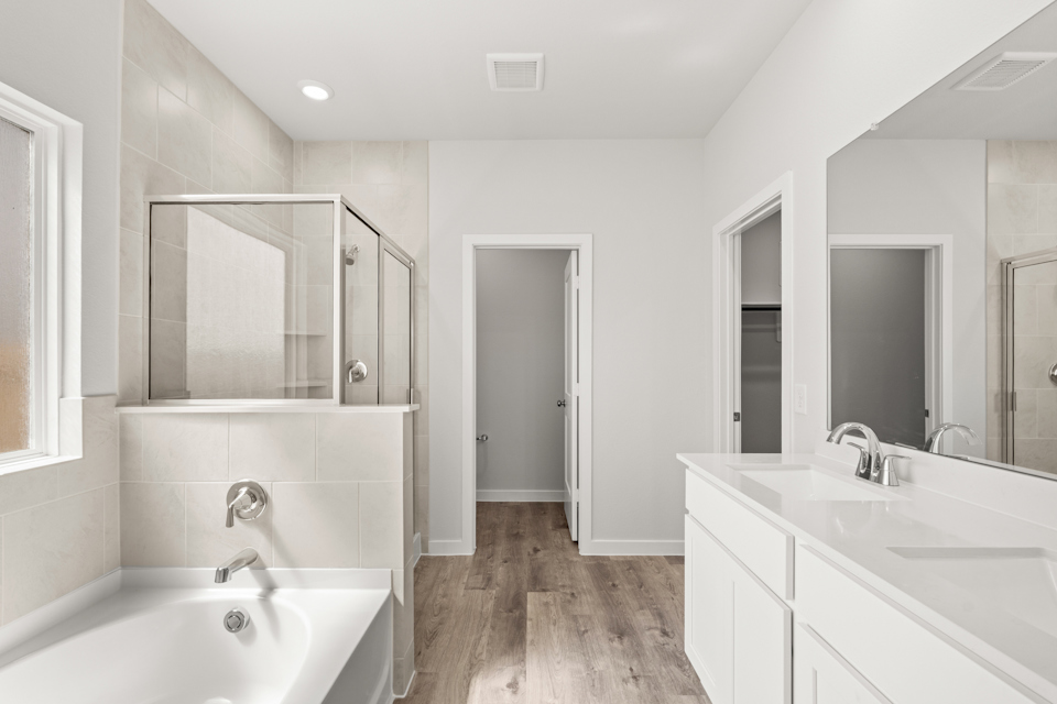 A bathroom with a tub sink and mirror.