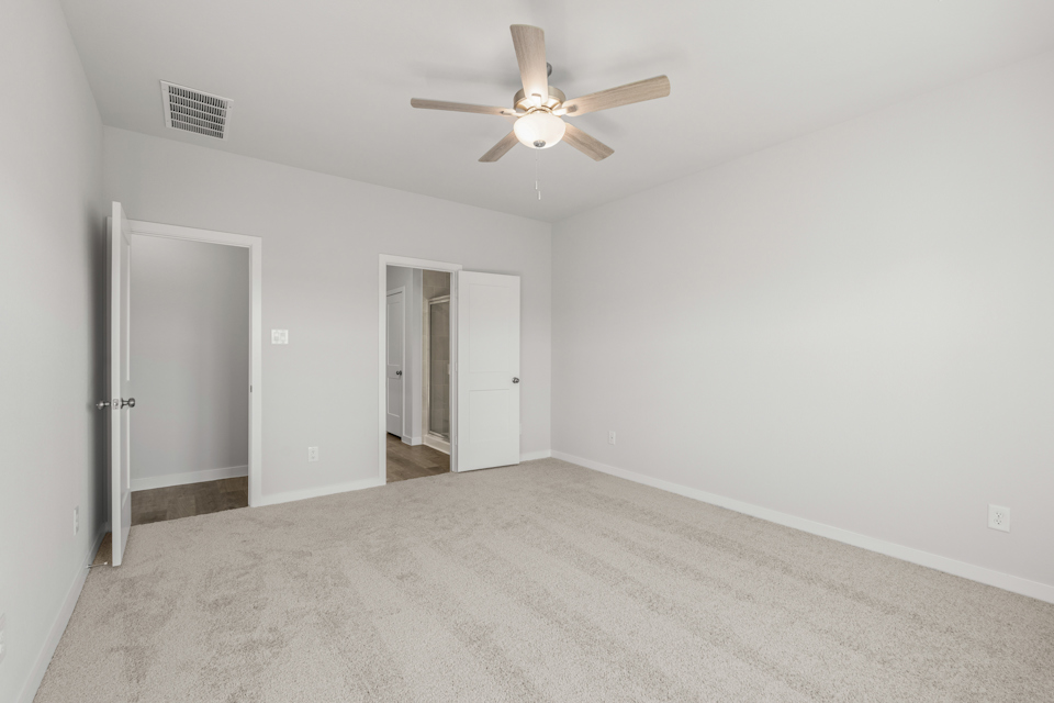 A room with a ceiling fan and a door.