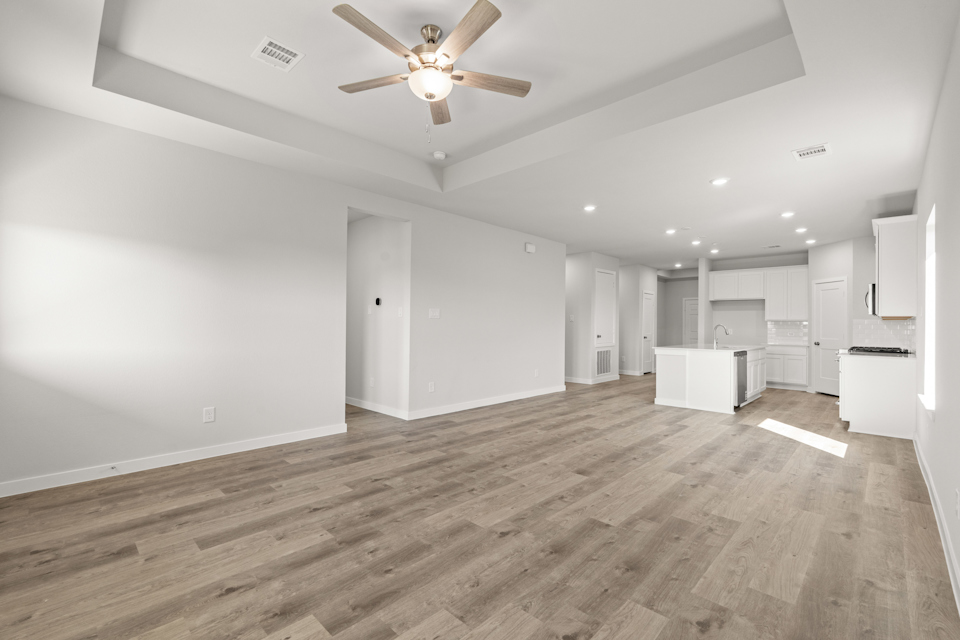 A large empty room with a ceiling fan and a wood floor.