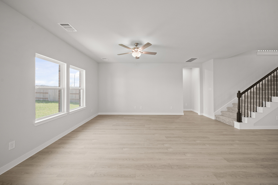 A room with a wood floor and a ceiling fan and a wood floor.