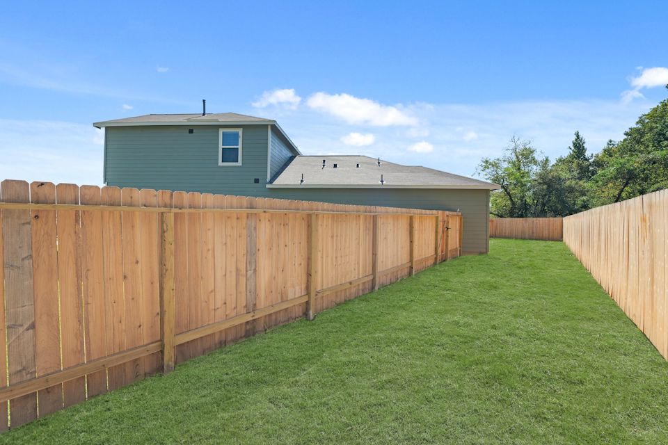 A fenced in yard with a house in the background.