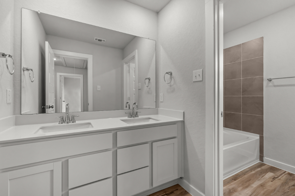 A bathroom with a tub sink and mirror.