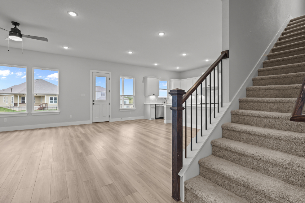 A large room with a wood floor and a wood staircase.