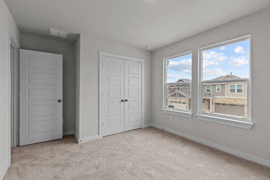 A room with white doors and a window with a view of a city.