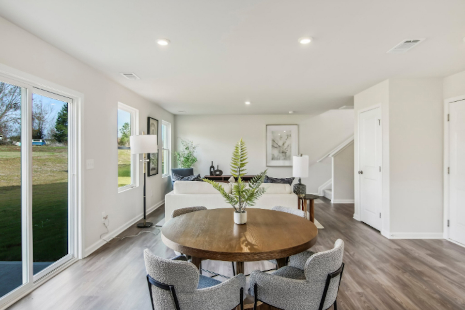 A dining room with a large glass door and a large table with chairs.